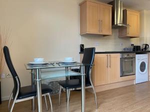 a kitchen with a glass table and chairs in it at 1 BED MODERN APARTMENT WITH FREE PARKING, SHEFFIELD CITY CENTRE in Sheffield