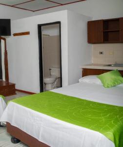 a bedroom with a bed and a bathroom with a toilet at hospedaje oasis central in Palmira