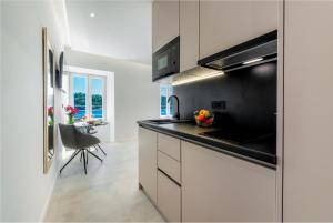 a kitchen with white cabinets and a black counter top at La Porta 2, seaview apartment in the center in Cavtat