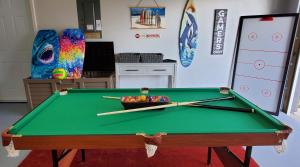 a green pool table with two cue sticks on it at Venice 3 Bedroom Luxury Home, Completely Renovated, 5 Star Rated - 10Mins to Beaches in Venice