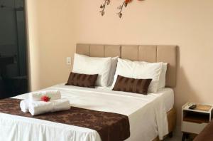 ein Schlafzimmer mit einem großen weißen Bett mit Handtüchern darauf in der Unterkunft Shalom Pousada Capitólio in Capitólio