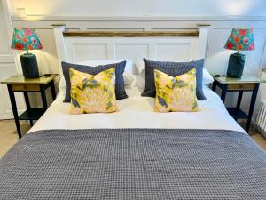 a bed with blue and yellow pillows and two lamps at Nine Cooper Lane, Holmfirth in Holmfirth