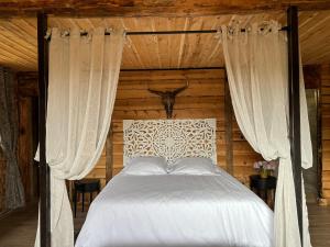 um quarto com uma cama com lençóis brancos e cortinas em Bastide De Mazan em Riez