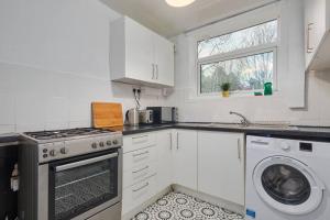 una cucina con armadi bianchi e una lavatrice/asciugatrice di Large home with free parking - 5 mins to St James' a Elswick