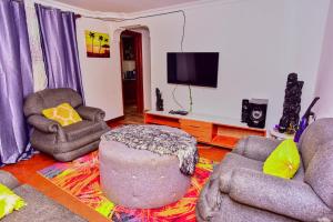 a living room with two chairs and a tv at NoorVilla in Arusha