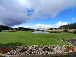 einen Golfplatz mit einem Teich und einem grünen Feld in der Unterkunft The Boathouse in Longmorn
