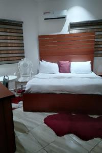 a bedroom with a large bed with a wooden headboard at Alim Royal Hotel and Suites in Abuja