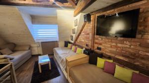 a living room with a couch and a tv on a brick wall at Konaci”Rile-Men” in Kopaonik