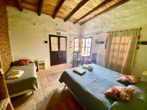 a bedroom with two beds and a table and a chair at Hosteria La Pushka in Purmamarca