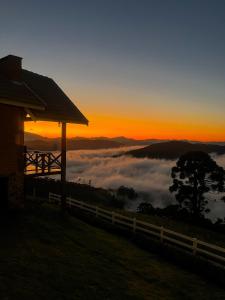 a cabin on top of a hill with a view of clouds at Chalé Pico da Mantiqueira in Sapucaí-Mirim