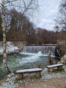 two benches sitting in front of a waterfall at Ubytovanie Janka in Turany