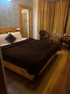 Asha Residency Shimla - Airport Road في شيملا: سرير كبير في غرفة بها كرسيين