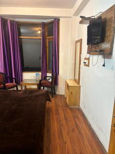 a living room with a bed and a tv on a wall at Asha Residency Shimla - Airport Road in Shimla