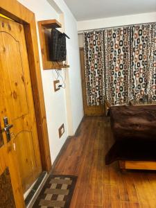 a living room with a couch and a television and a door at Asha Residency Shimla - Airport Road in Shimla