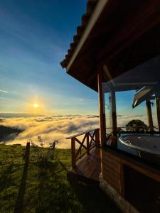 a hot tub on top of a hill with the sunset at Chalé Pico da Mantiqueira in Sapucaí-Mirim