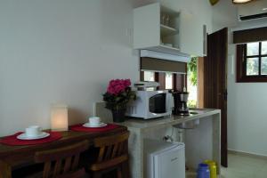 a kitchen with a counter with a microwave and a table at Vila dos Caetés - Suíte 02 - Barra do Sahy in Barra do Sahy