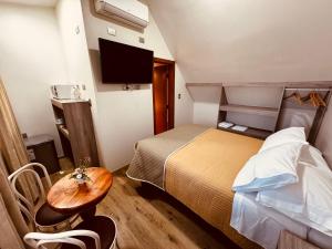 Habitación pequeña con cama y mesa en Hotel Casona Los Colonos en Valdivia
