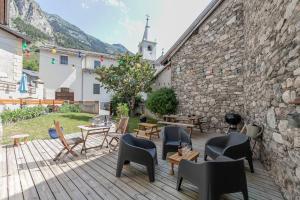 a patio with chairs and tables and a stone wall at Côté-Bourget 2 pers L'AIGUILLE D'ORAN proche La Norma Aussois ! in Villarodin-Bourget