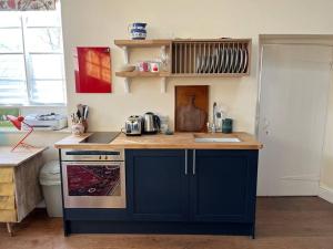 a kitchen with a blue island in a room at Charming Old Schoolroom Studio in Daventry