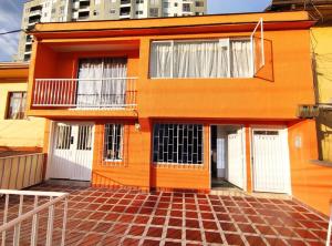 ein orangefarbenes Haus mit weißen Türen und Ziegelboden in der Unterkunft Aparta Estudio nuevo a 2 calles de Milán in Manizales