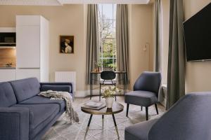 a living room with a blue couch and two chairs at Sonder Royal Garden in Edinburgh