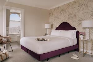 um quarto com uma grande cama branca e uma cabeceira de cama roxa em Sonder Royal Garden em Edinburgo