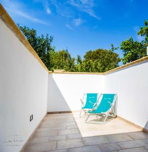 two blue chairs sitting on a white wall at Villette Calliope in Torre Specchia Ruggeri
