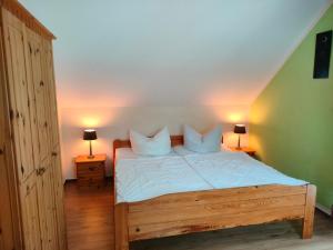 una camera da letto con un letto con lenzuola bianche e due lampade di Lenzer Ferienidyll am Plauer See a Lenz