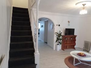 a hallway with a staircase and a living room at Shepherds Spacious House 4-Beds in Romford