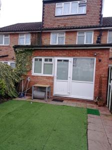 a brick house with a white door and a lawn at Shepherds Spacious House 4-Beds in Romford