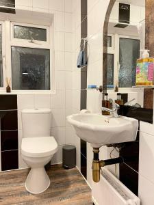 a bathroom with a toilet and a sink at Shepherds Spacious House 4-Beds in Romford