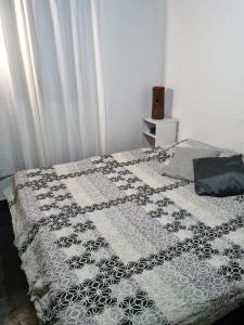 a bed with a black and white quilt on it at Cantinho da Eli - Pousada com Piscina in Mairiporã