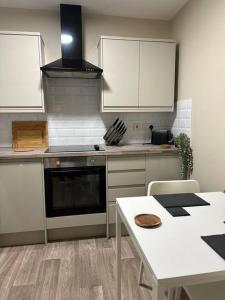 a kitchen with white cabinets and a table and a stove at Well Equipped Apartment In Stoke on Trent in Stoke on Trent
