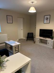 a living room with a flat screen tv and a table at Well Equipped Apartment In Stoke on Trent in Stoke on Trent