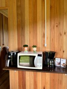 a microwave sitting on a counter in a kitchen at CABANAS BELVEDERE SERRA DO RiO DO RASTRO in Lauro Müller