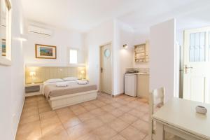 a white bedroom with a bed and a kitchen at Rocco's studios in Antiparos