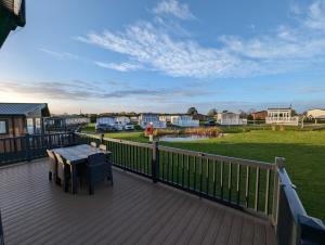 a wooden deck with a table and a view of a yard at Morrelo View 24, Cherry Tree Holiday park. in Great Yarmouth