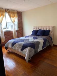 a bedroom with a bed with blue pillows and a window at Dulce Hogar 01 in Loja