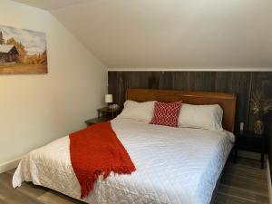 ein Schlafzimmer mit einem Bett mit einer roten Decke darauf in der Unterkunft Le Kamillō in Notre-Dame-Des-Bois