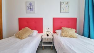 two beds with red headboards in a room at Terraza privada con impresionantes vistas al mar in Benidorm