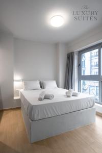 een slaapkamer met een groot bed met witte lakens en een raam bij WeStay Apartments, The Luxury Suites in Thessaloniki