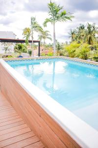 a swimming pool with a wooden fence and palm trees at Refugio del Mar Luxury Hotel Boutique in Bucerías