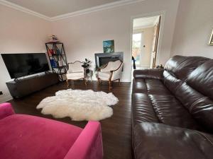 sala de estar con sofá de cuero y alfombra blanca en Lovely 3 bedrooms house 4 guests en Beverley