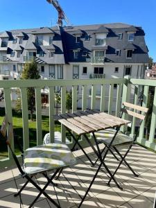 stół i krzesła na balkonie z budynkiem w obiekcie Joli appartement avec parking et balcon w mieście Touques