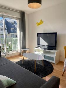 een woonkamer met een bank en een tv bij Joli appartement avec parking et balcon in Touques