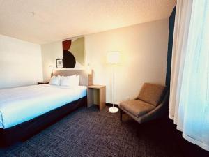 um quarto de hotel com uma cama e uma cadeira em Spark by Hilton Modesto em Modesto
