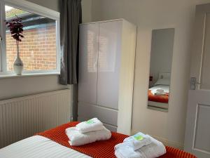 a bedroom with two towels on a bed and a mirror at Elegant Serviced Apartment with Parking in Oxford in Oxford