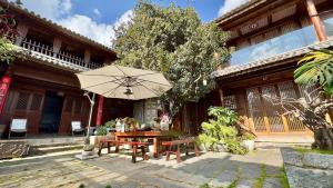 a table with an umbrella in front of a building at Qingxin Courtyard Art Guesthouse in Dali