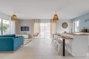 Il comprend une cuisine et un salon avec une table et un canapé bleu. dans l'établissement Clair Jeanne - Charmante maison neuve, à Notre-Dame-de-Monts