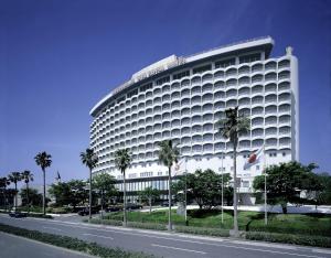鹿兒島的住宿－鹿兒島太陽皇家酒店，一条大白色的建筑,在道路前有棕榈树
